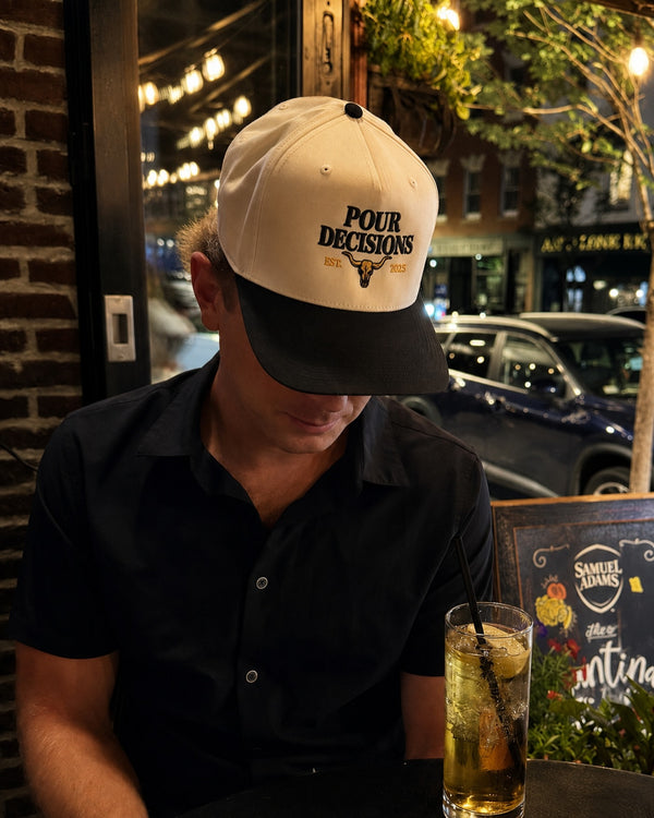 Pour Decisions SnapBack after dark against a brick wall